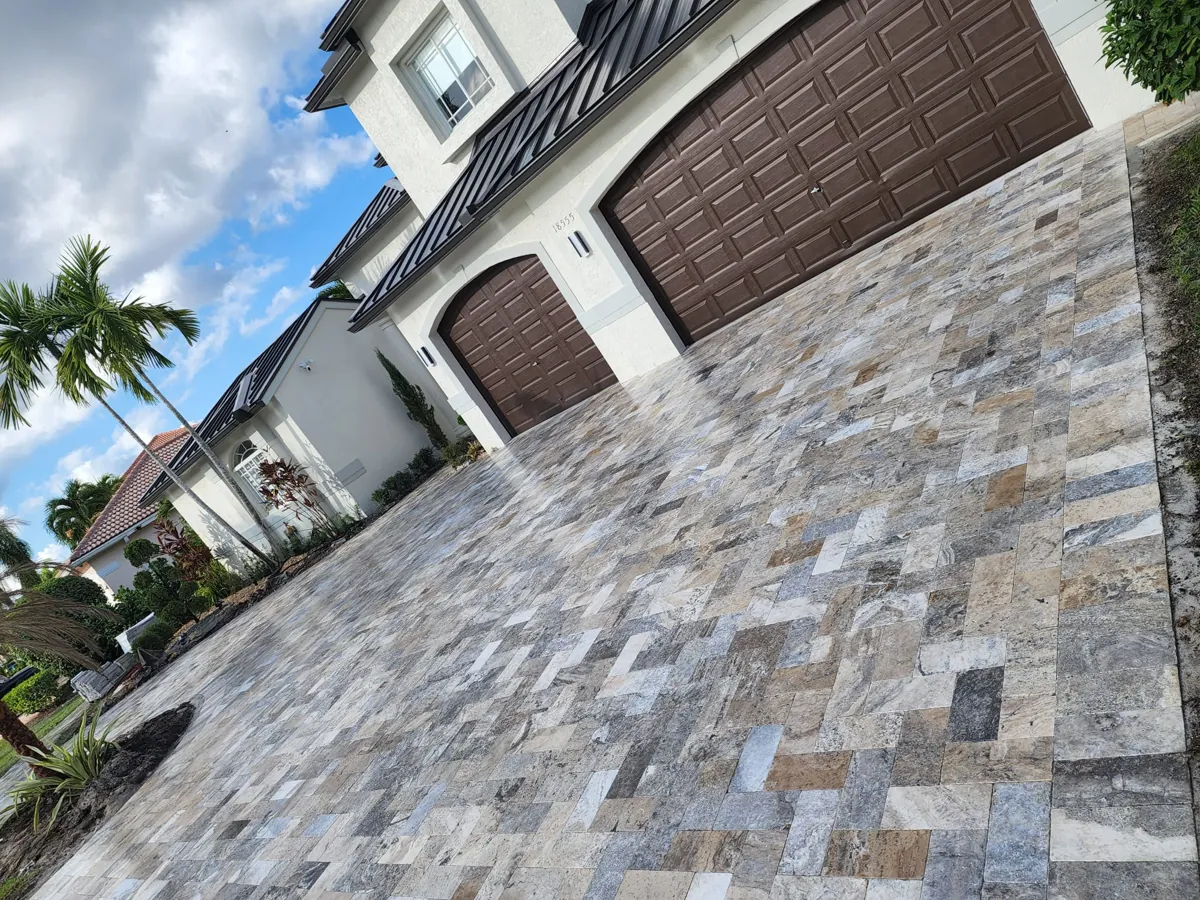 Multi-color slate-toned pavers sweeping toward brown garage doors