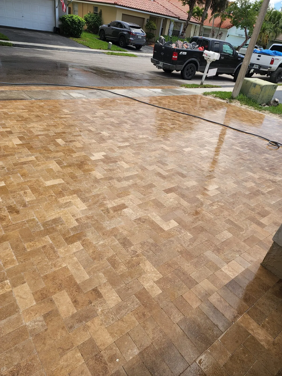 Warm travertine-toned driveway surface shining after cleaning