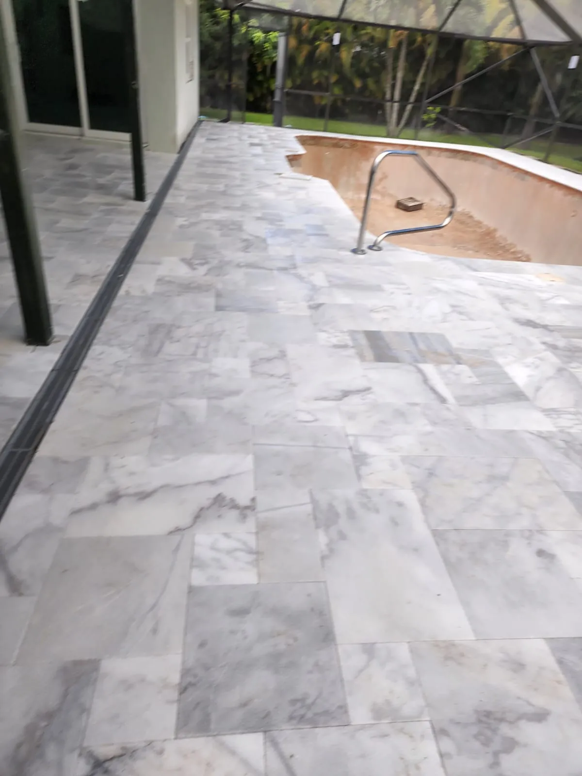 Veined marble-look paving along a screened pool enclosure