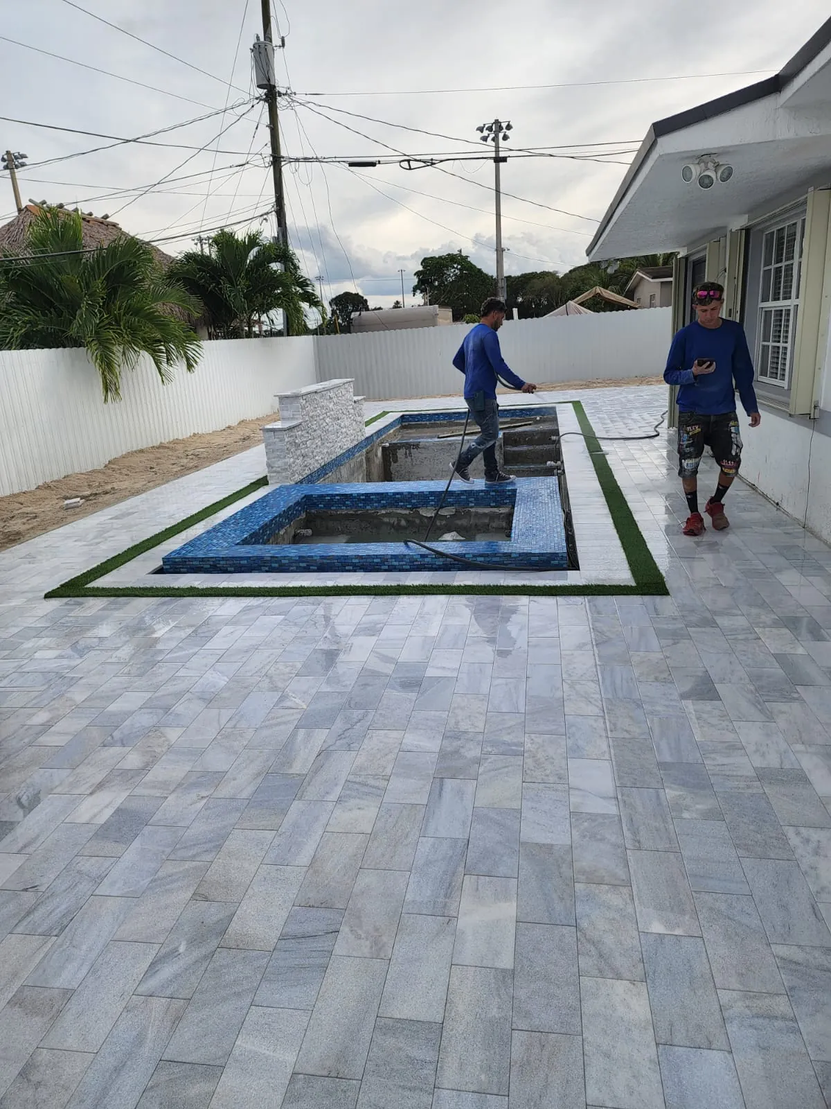 Gray stone surface around a raised spa with a turf border