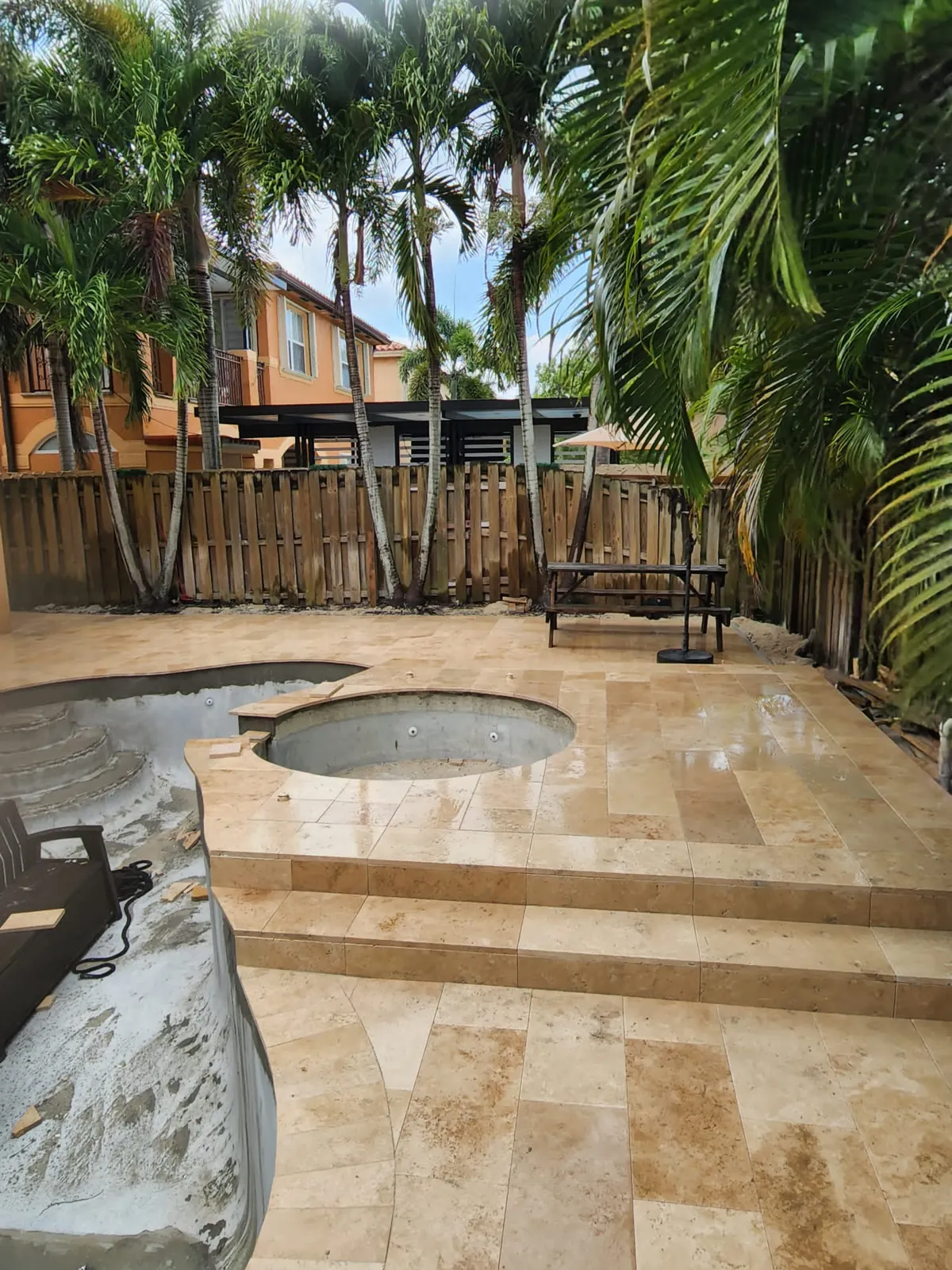 Travertine steps and spa surround under construction in a fenced yard